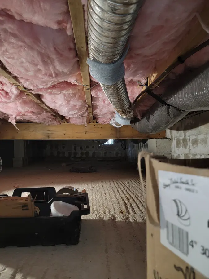 Before: Flexible dryer duct hanging under floor joists in a crawlspace