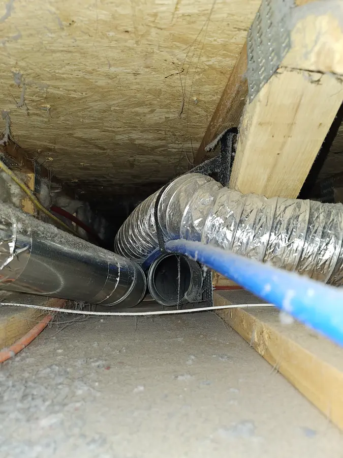 Before: Kinked foil flex ducts tangled between ceiling joists