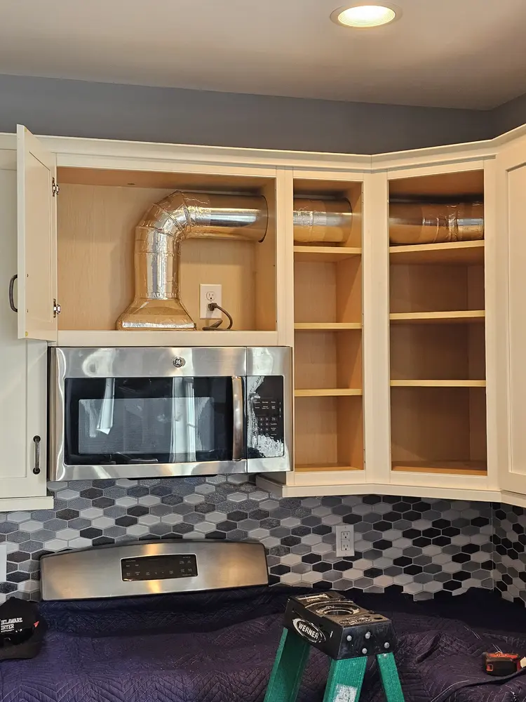Over-the-range microwave installed with metal exhaust venting in the cabinet above